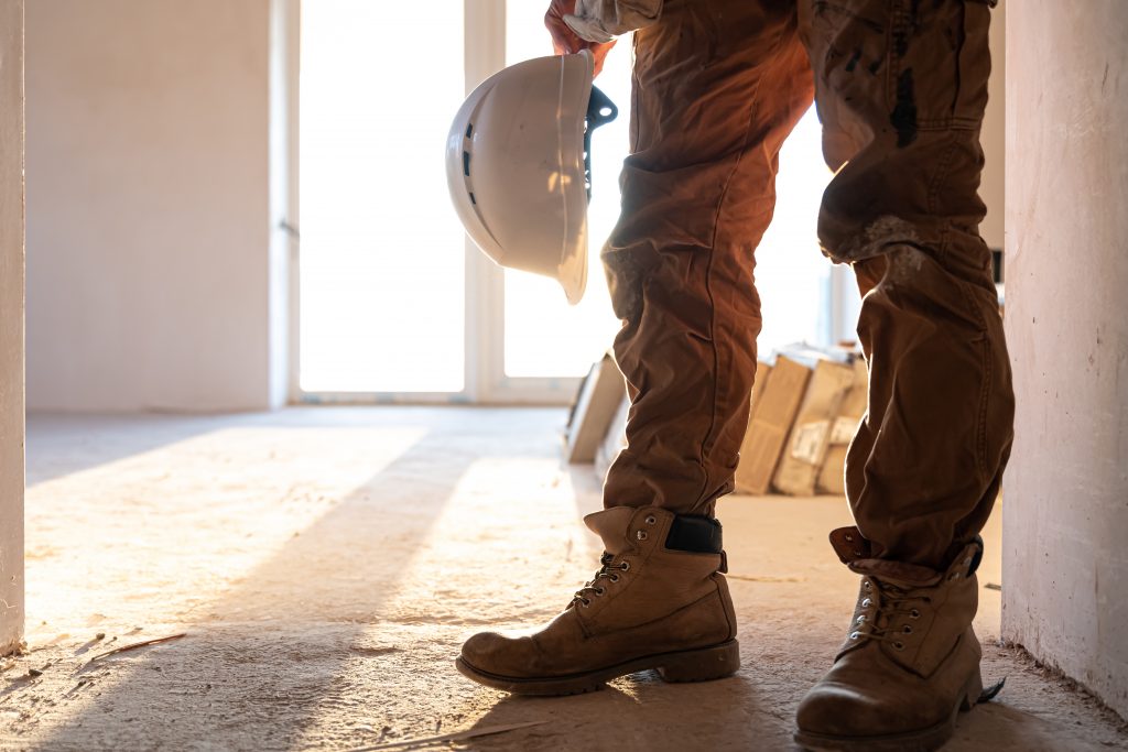 A man builder in work clothes at a construction site, copy space.